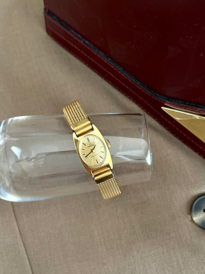 Omega Geneve oval dial women’s watch displayed on glass beside a red jewellery box