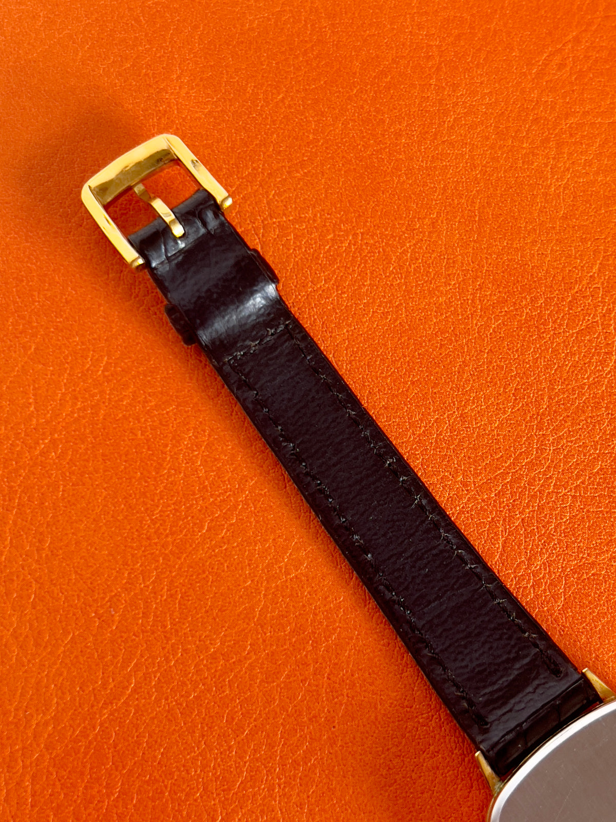Angled view of a vintage Omega gold-tone cushion watch with champagne dial.