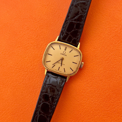 Caseback detail of a vintage Omega gold-tone cushion watch with champagne dial.