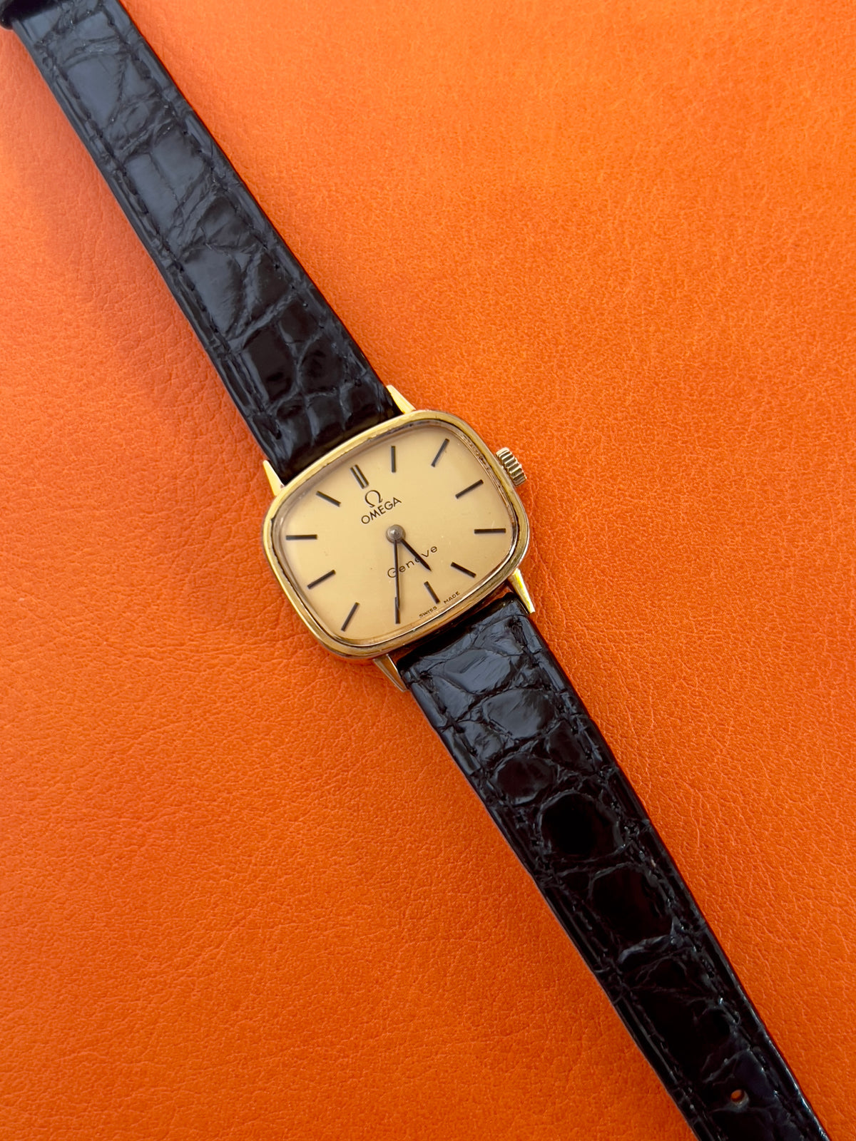 Front view of a vintage Omega gold-tone cushion watch with champagne dial.