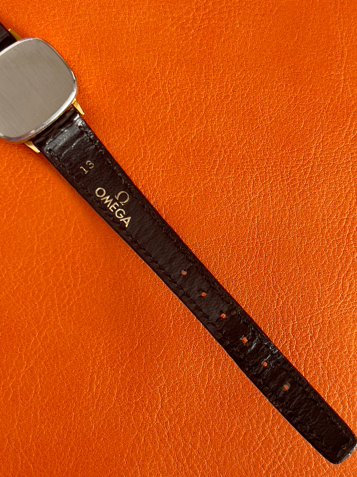 Wrist shot of a vintage Omega gold-tone cushion watch with champagne dial.