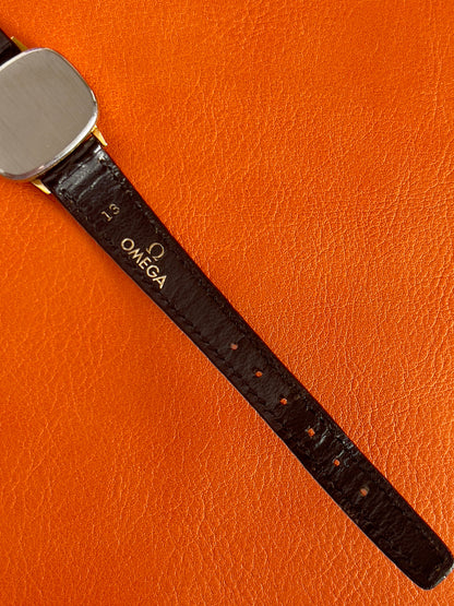 Wrist shot of a vintage Omega gold-tone cushion watch with champagne dial.