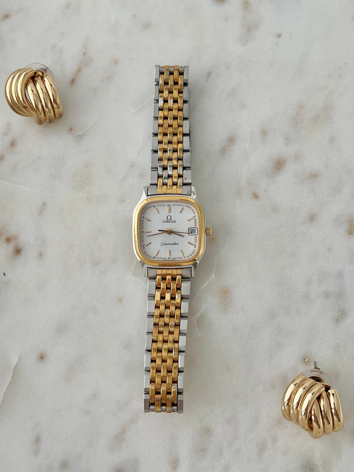 Front view of Omega Seamaster Brest two tone women’s watch with white textured dial and integrated bracelet