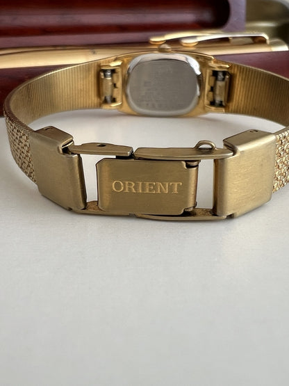 Orient signed folding clasp on the gold tone mesh bracelet, with the caseback and bracelet underside visible.