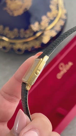 Angled close-up video of the Omega De Ville champagne dial gold watch, showing its gold tone case, fluted crown and black textured strap.
