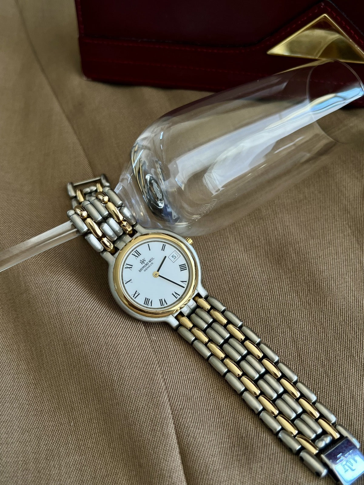 Front view of Raymond Weil Fidelio watch showing white dial, black Roman numerals and gold tone bezel