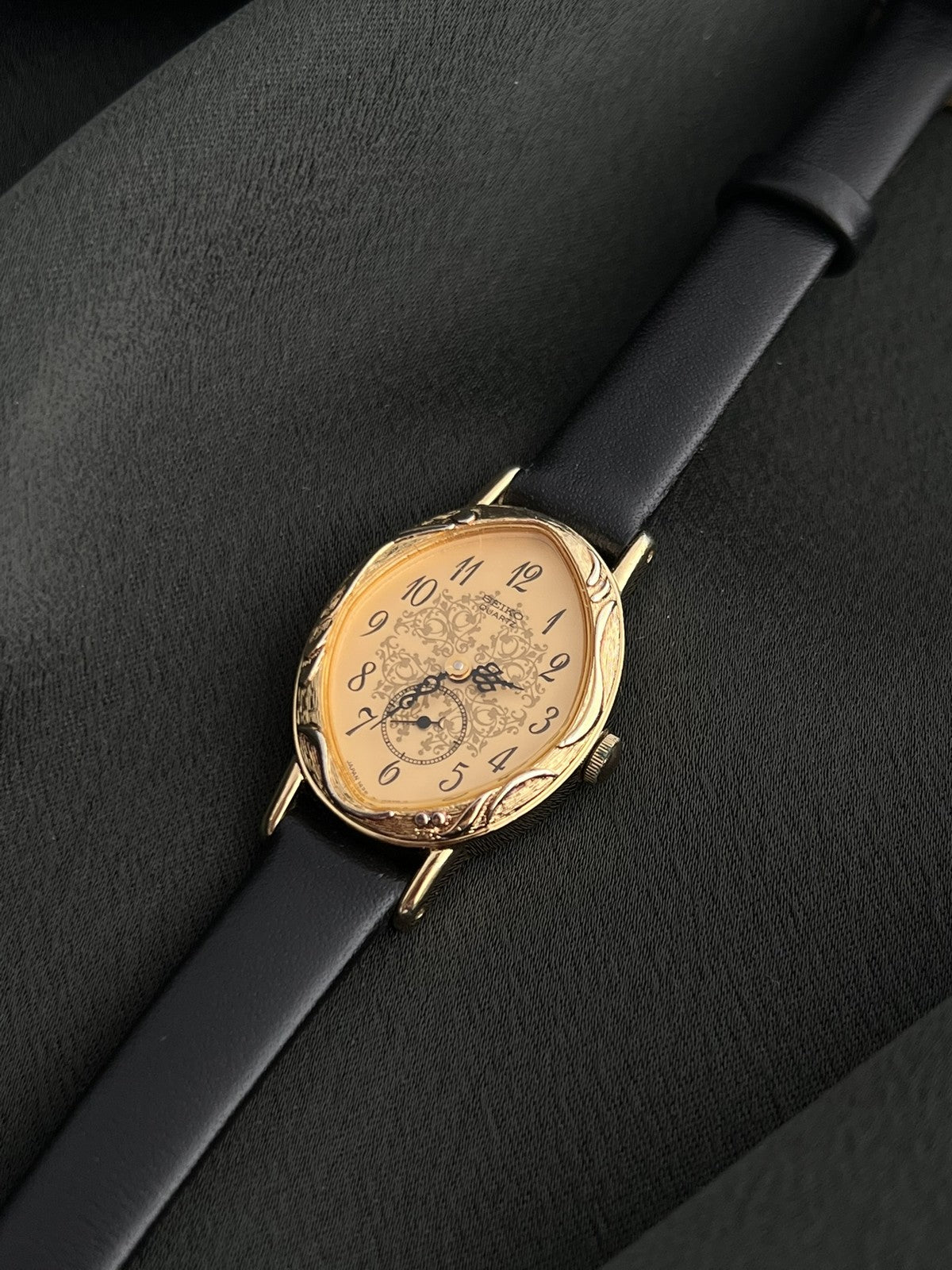 Angled dial view of the Seiko 1E20-0370 with black Arabic numerals and decorative floral pattern