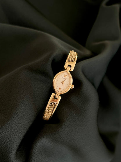Seiko petite gold-tone oval quartz watch with textured bracelet, front view
