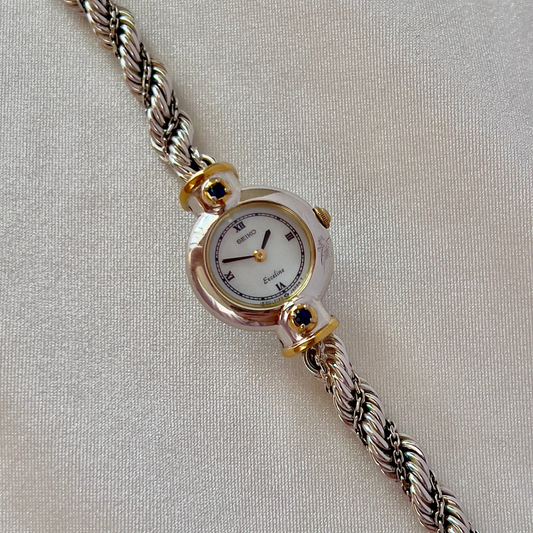 Seiko Exceline women’s watch with a white Roman numeral dial, two-tone case, and original rope bracelet.