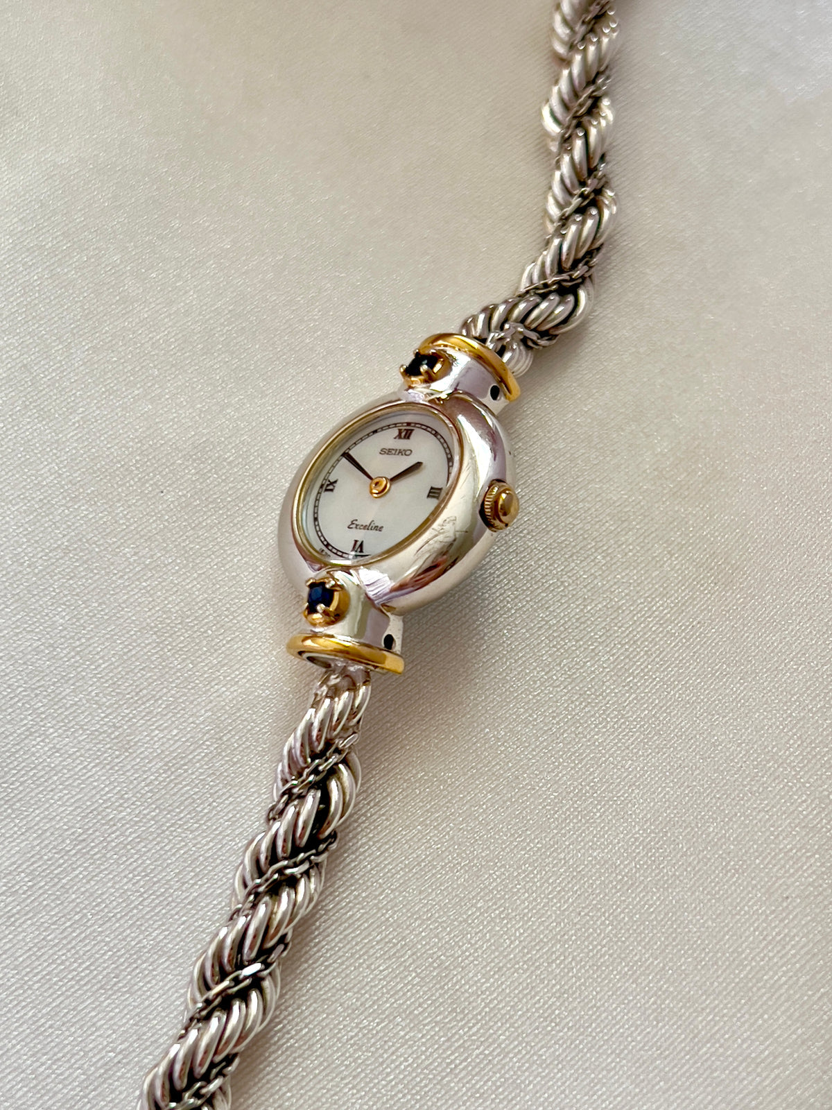 Seiko Exceline women’s watch with a white Roman numeral dial, two-tone case, and original rope bracelet.