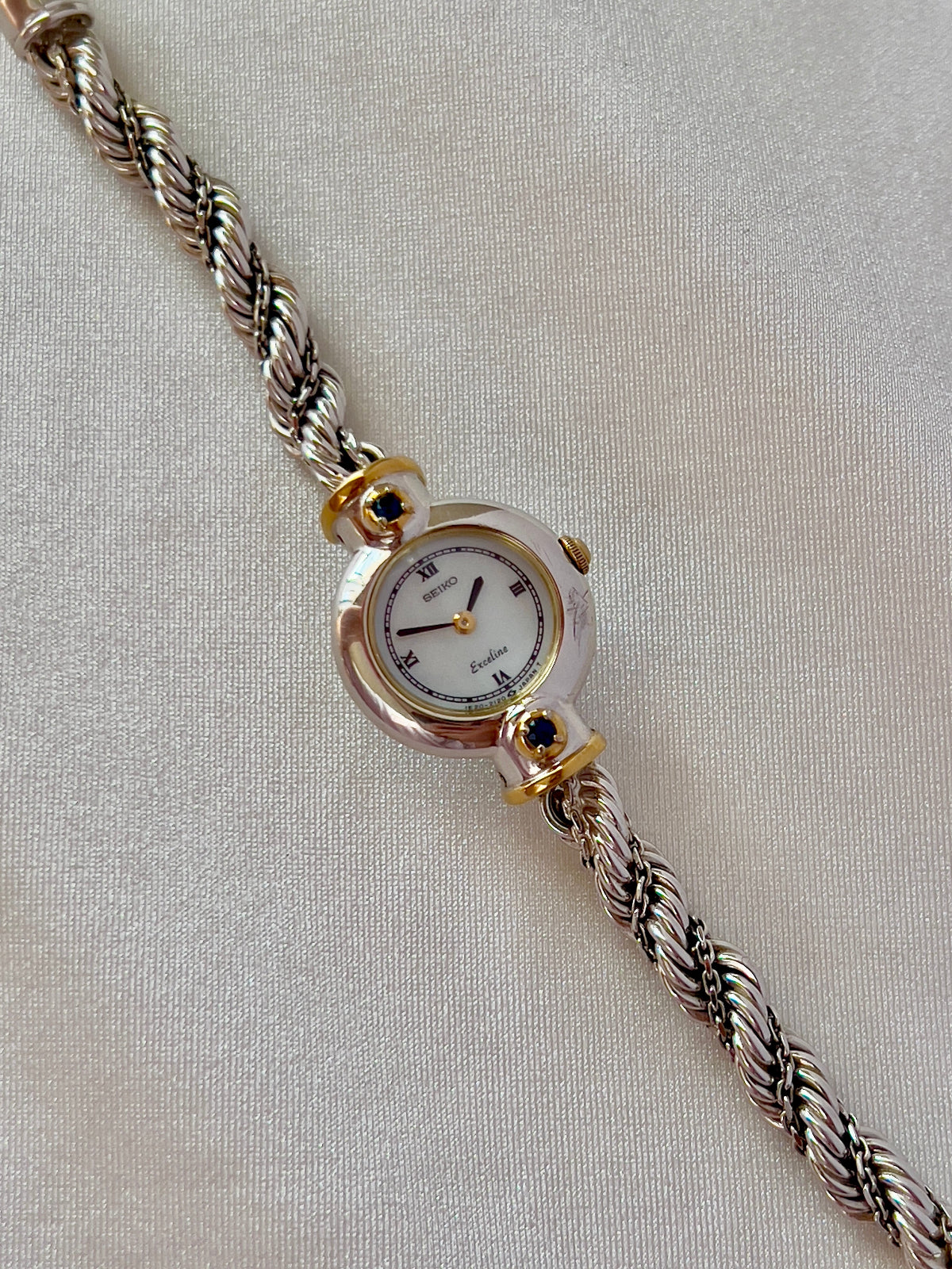 Seiko Exceline women’s watch with a white Roman numeral dial, two-tone case, and original rope bracelet.