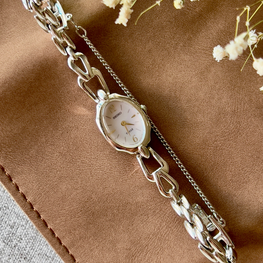 Seiko Tisse women’s watch with a light pink pearl dial, oval case, and linked bracelet.