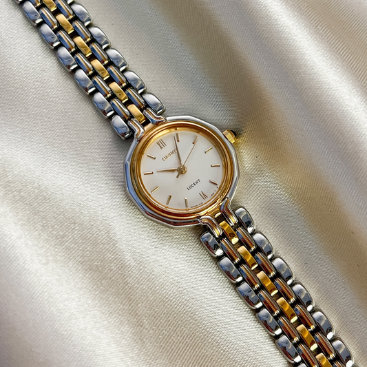 Seiko Lucent women’s watch with a champagne dial, black stone crown, and two-tone link bracelet.