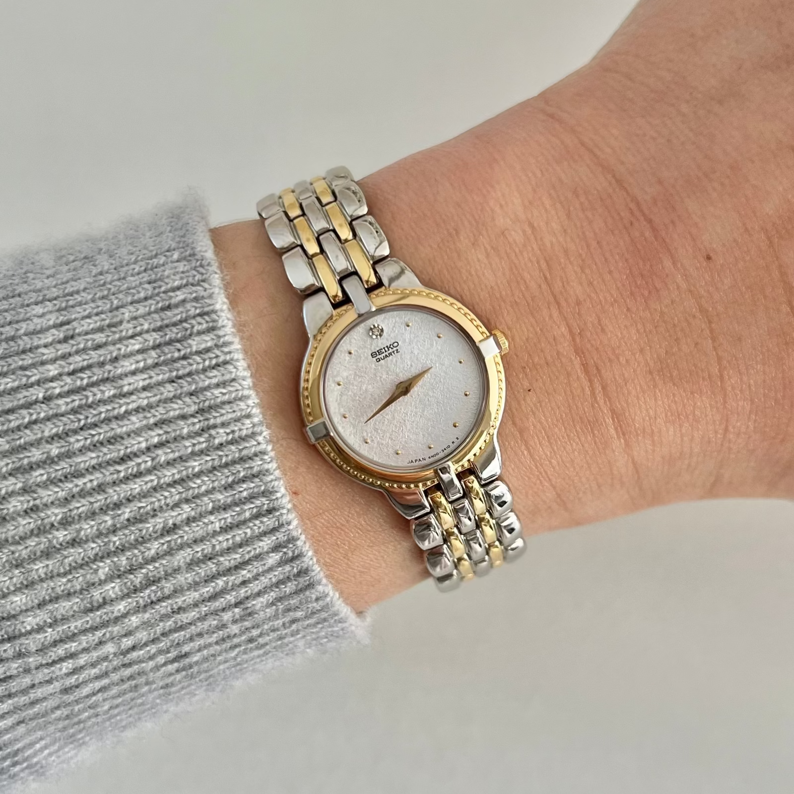 Front dial view of the Seiko 4N00-0910 women’s watch, showing its silver textured face, diamond accent at 12 and gold-tone bezel.