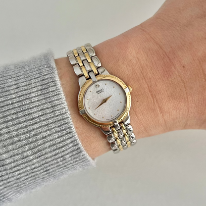 Front dial view of the Seiko 4N00-0910 women’s watch, showing its silver textured face, diamond accent at 12 and gold-tone bezel.