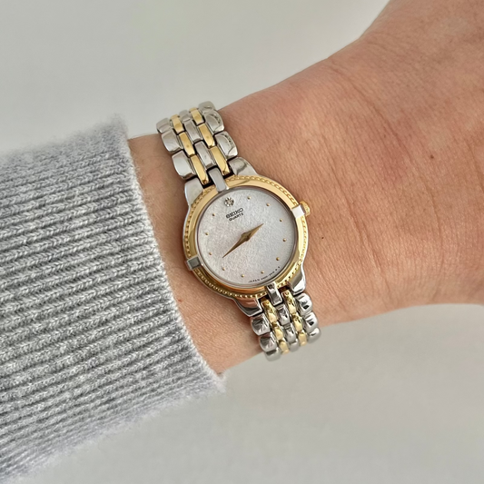 Front dial view of the Seiko 4N00-0910 women’s watch, showing its silver textured face, diamond accent at 12 and gold-tone bezel.