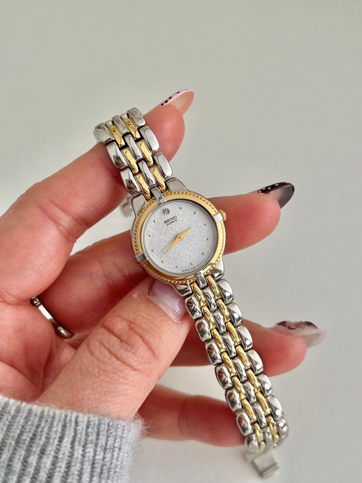 Close-up of the Seiko 4N00-0910 silver textured dial with gold dot markers and a diamond accent at 12.