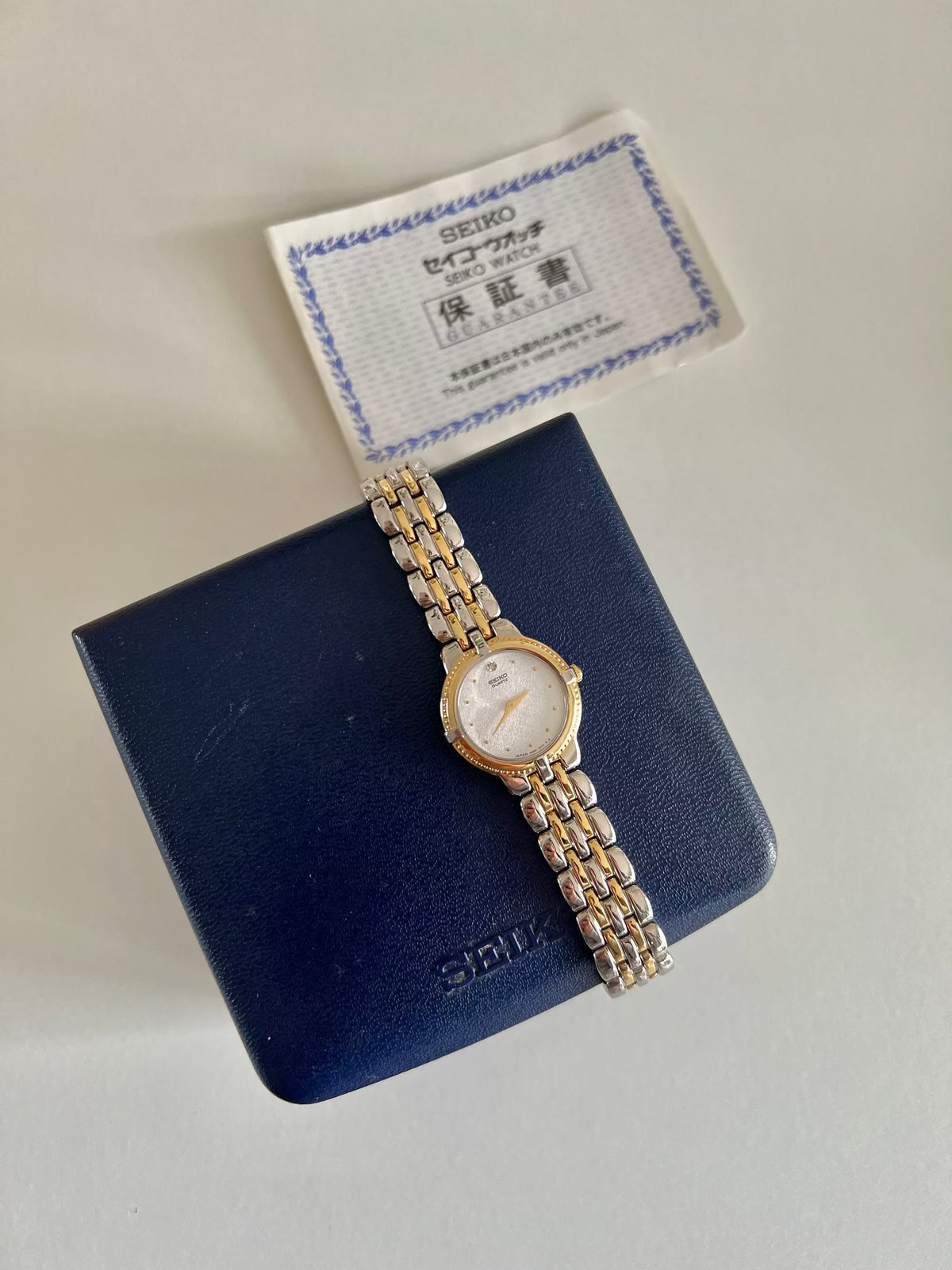 Angled view of the Seiko 4N00-0910 two-tone women’s watch with sculpted case and integrated bracelet.