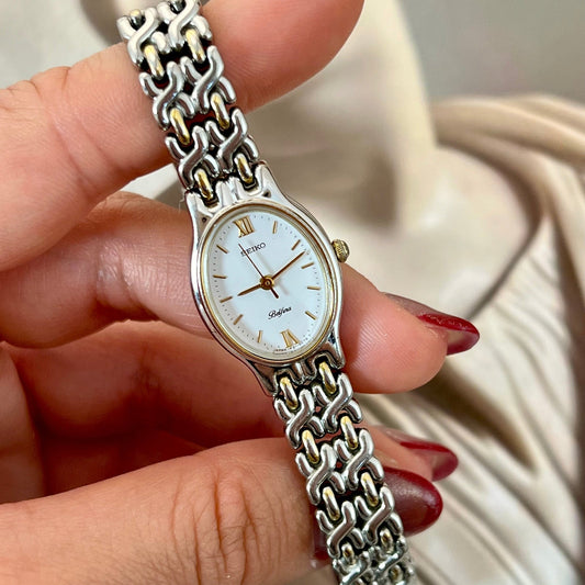 Front view of the Seiko Belfina two-tone oval watch with white dial.