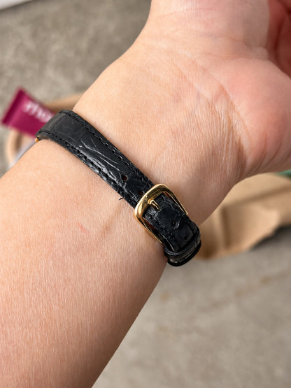 Black leather strap and gold tone pin buckle of the Seiko watch, viewed on wrist.