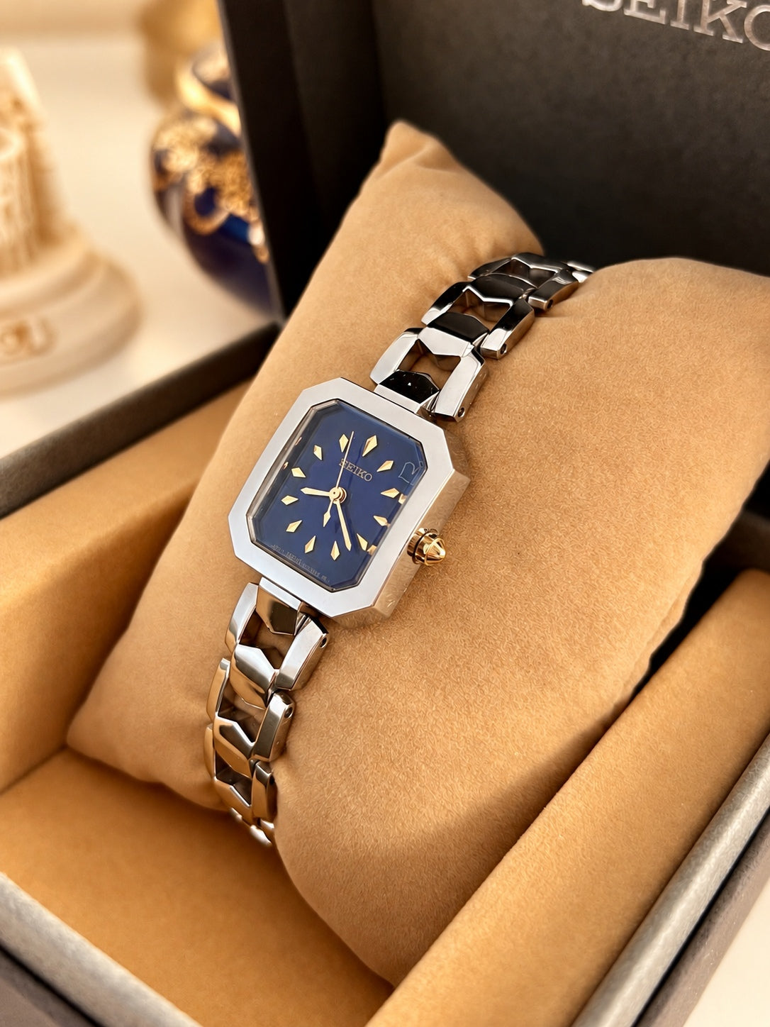 Close view of the blue Seiko dial with gold lozenge markers, outlined heart detail and clipped corner silver case