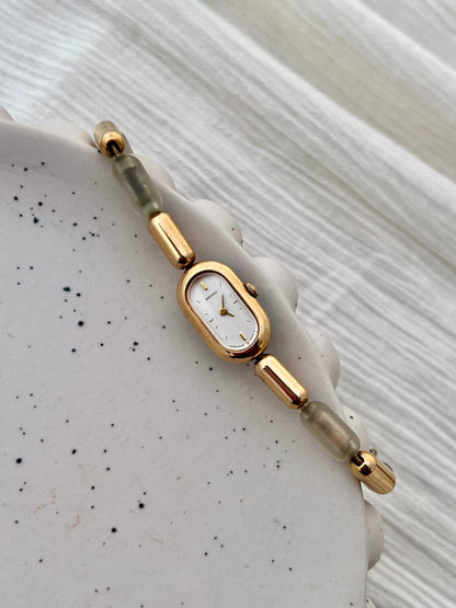 Front view of the Seiko capsule watch with gilt hands and a distinctive resin-segment bracelet.