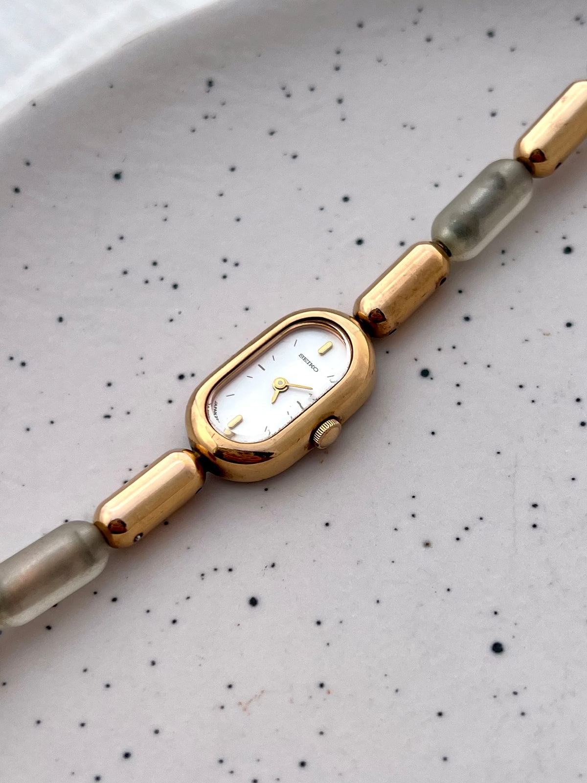 Angled view of the Seiko gold-tone capsule case and translucent resin bracelet links.