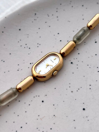 Angled view of the Seiko gold-tone capsule case and translucent resin bracelet links.