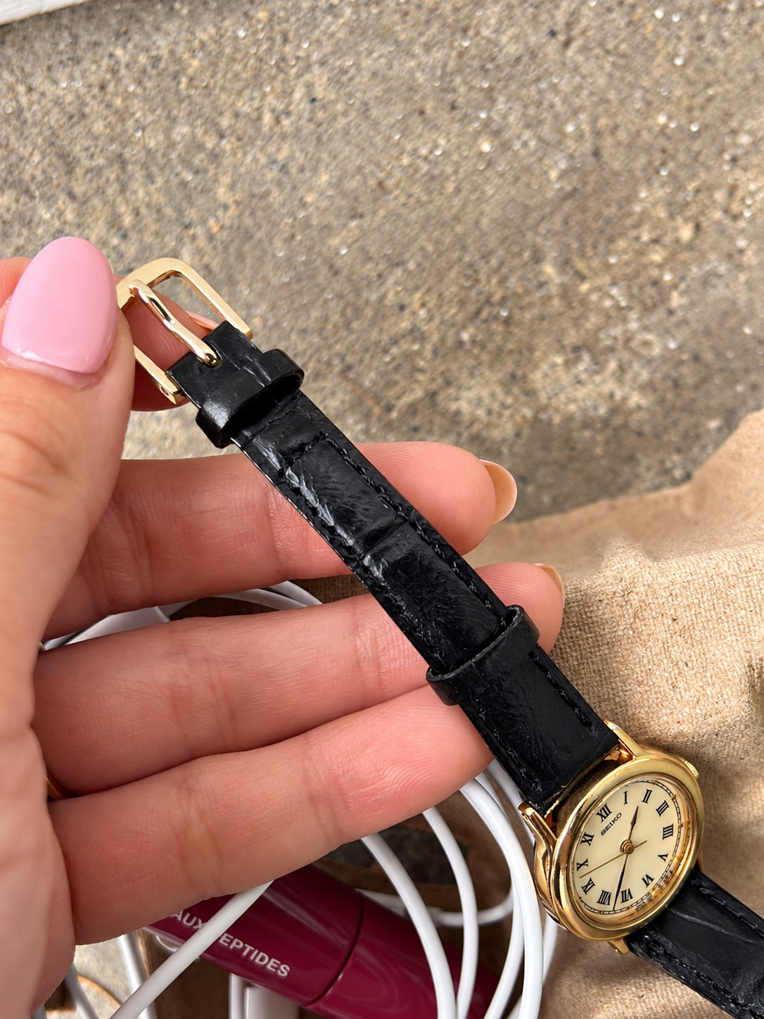 Seiko cream Roman dial watch showing the black leather strap, keepers and gold tone pin buckle.