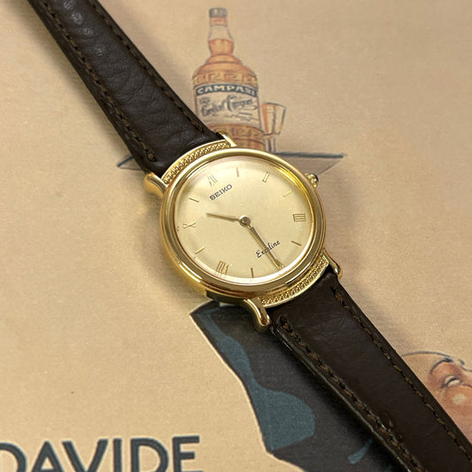 Front view of the Seiko Exceline gold-tone watch with champagne dial, beaded bezel and brown leather strap.