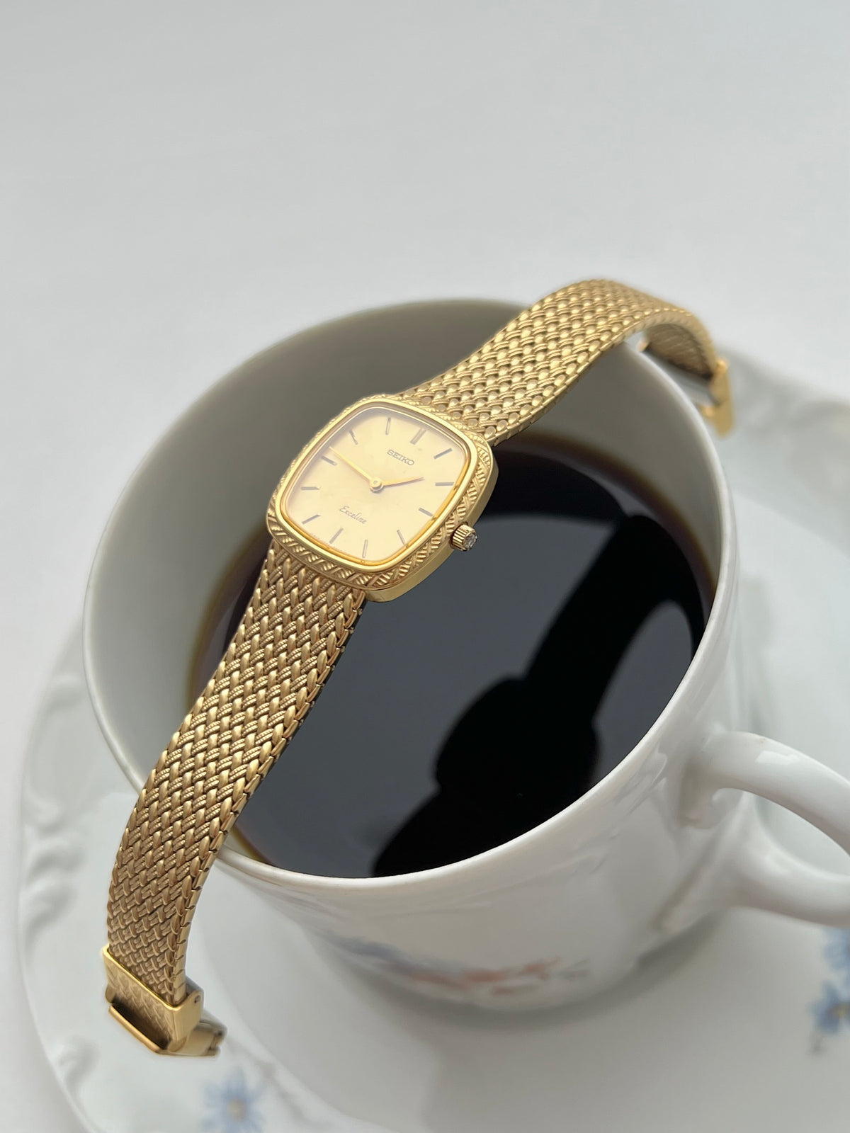 Seiko Exceline gold mesh bracelet watch shown on a wrist.