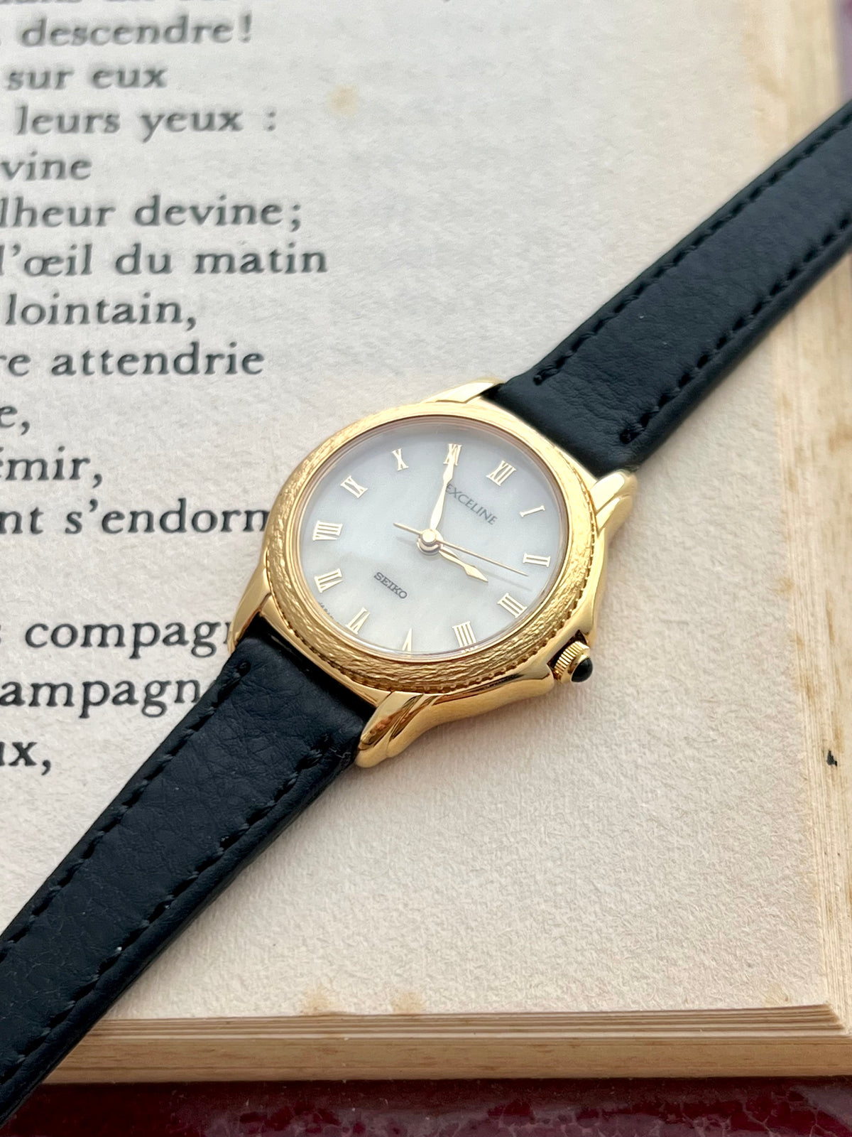 Seiko Exceline gold Roman dial watch shown on a wrist.
