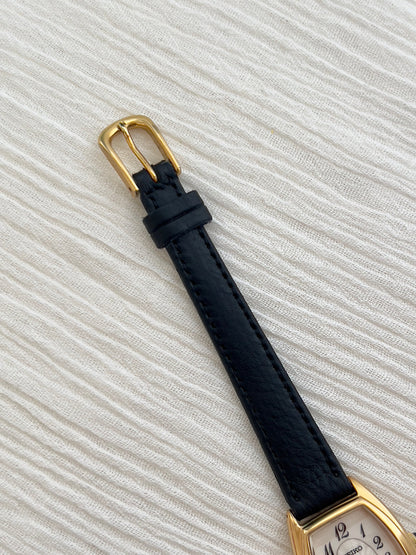Seiko Exceline Gold Tonneau Women’s Watch with Arabic Dial — gold tone buckle and black strap.