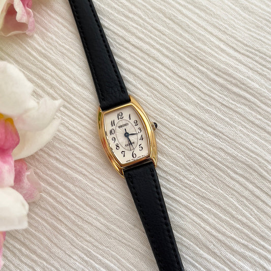Front view of the Seiko Exceline gold-tone tonneau watch with oval guilloche dial.