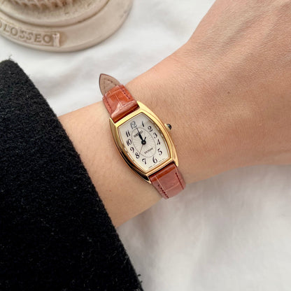 Seiko Exceline women’s watch with gold tone tonneau case, white dial, black Arabic numerals and brown leather strap.