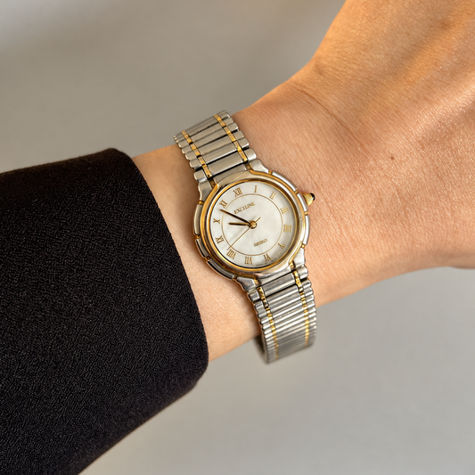 Seiko Exceline two tone Roman numeral mother of pearl dial watch on wrist in golden hour light, square hero