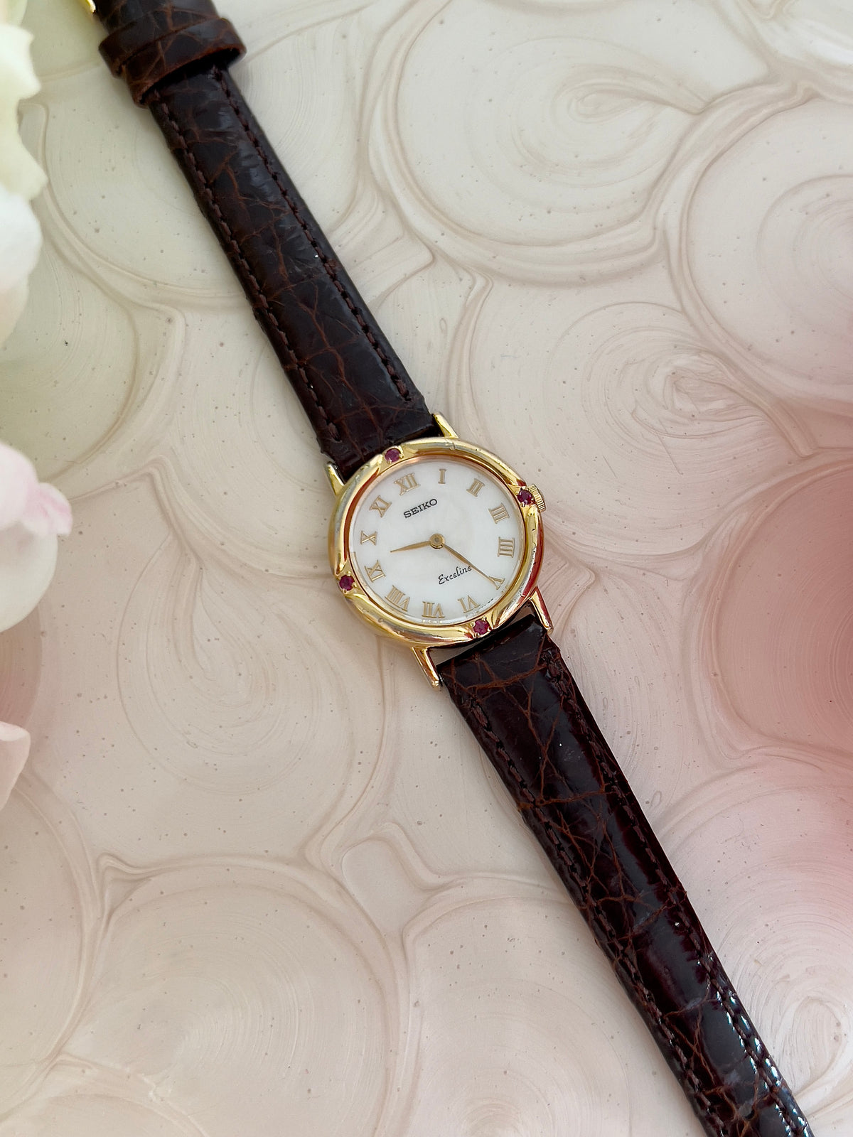 Seiko Exceline Mother of Pearl Women’s Watch with Ruby Accents — front view of Roman numeral dial.