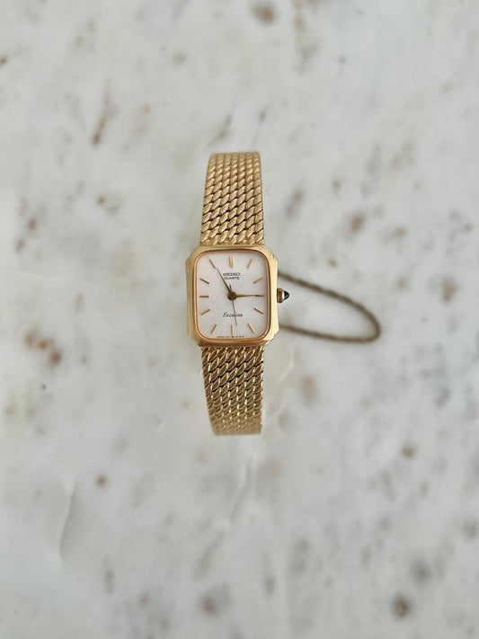 Front view of the Seiko Exceline rectangular gold-tone watch with textured champagne dial.