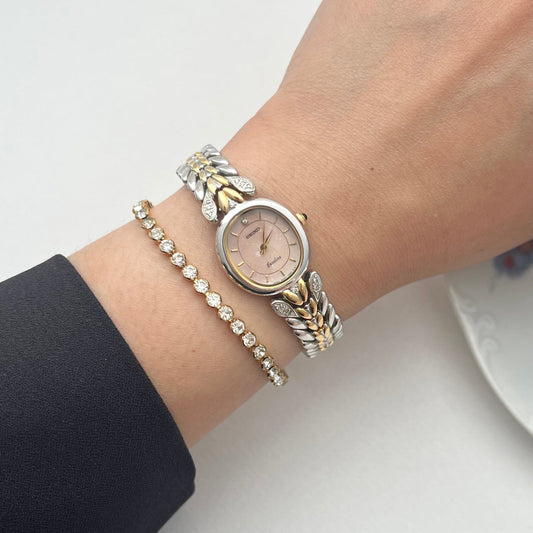 Seiko Exceline oval watch with salmon stardust dial and diamond leaf bracelet shown on a wrist.