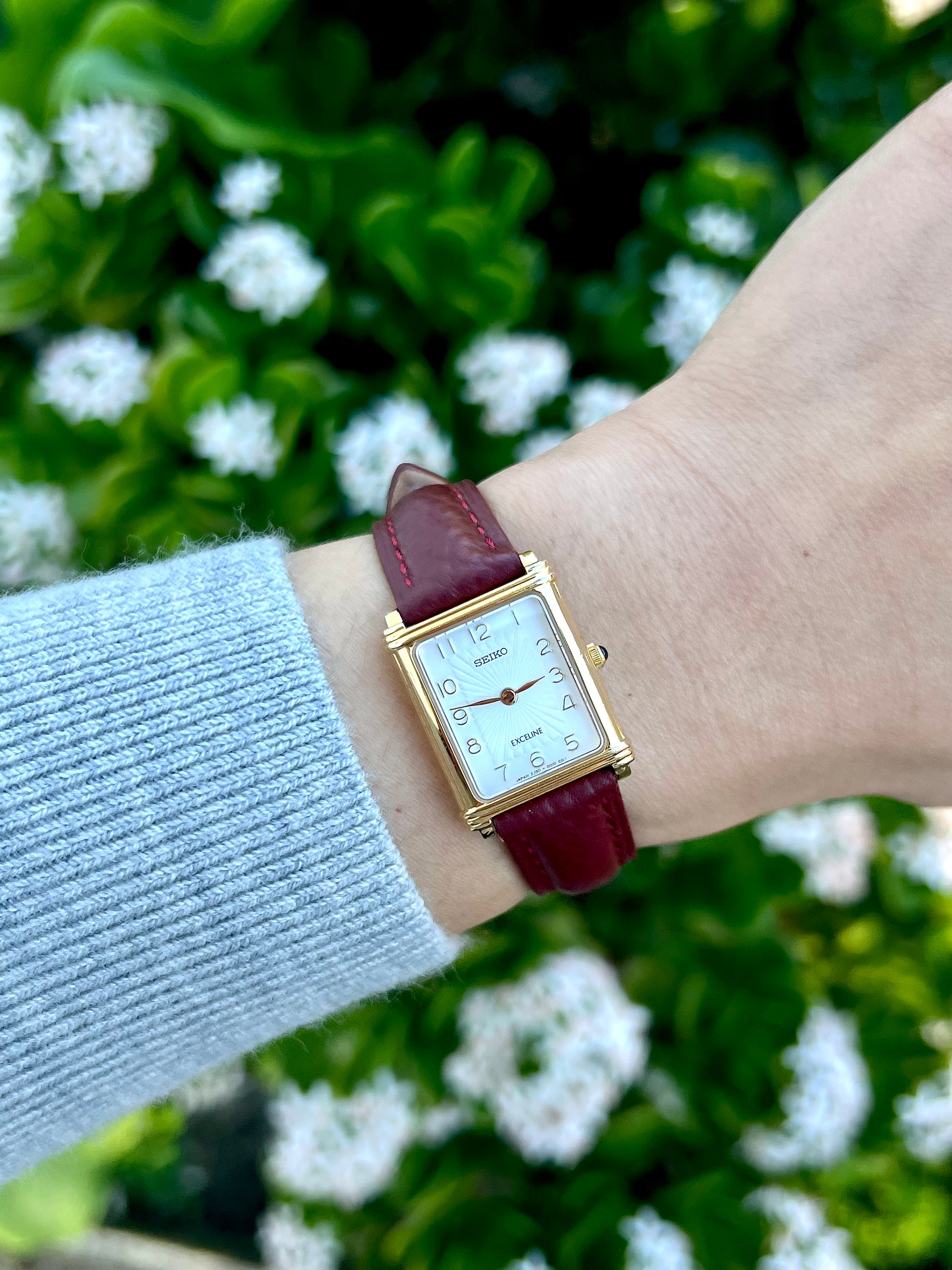 Seiko Exceline square gold tone women’s watch worn on wrist with burgundy leather strap