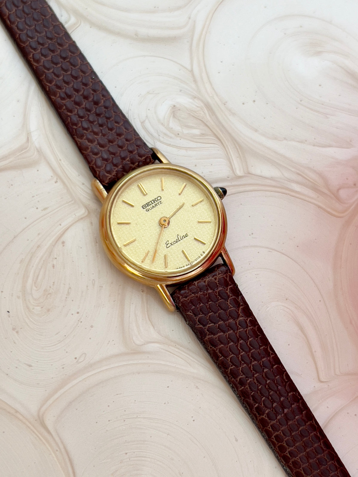 Seiko Exceline gold-tone watch shown on a wrist.