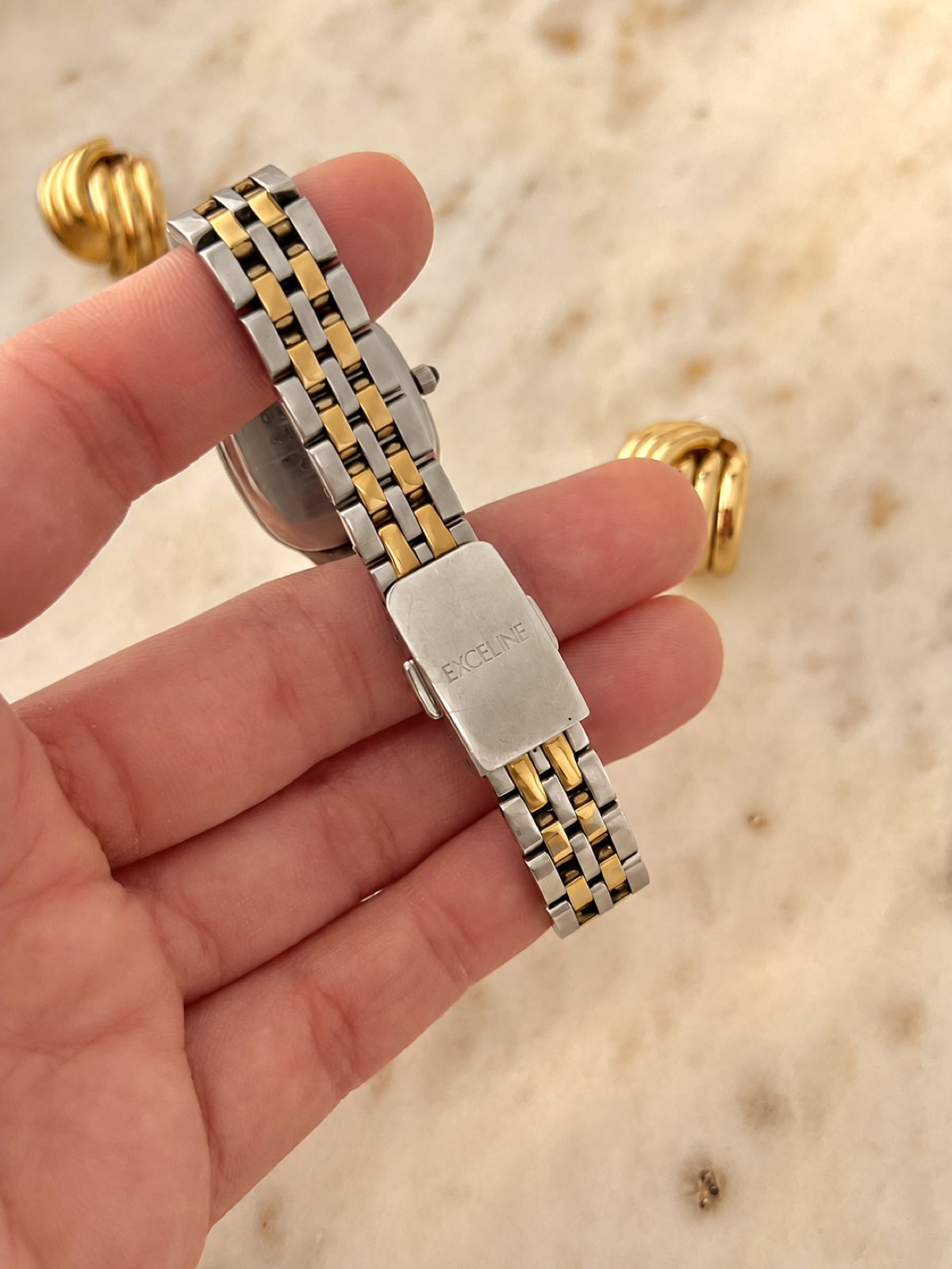 Handheld reverse detail of Seiko Exceline signed clasp and two tone bracelet, gently warmed colour balance
