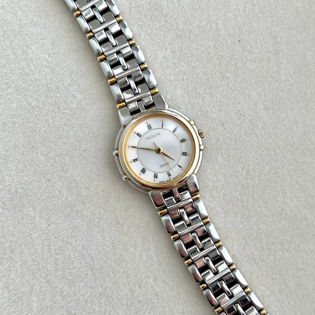 Seiko Exceline Silver watch with a white face on a light gray background and claws