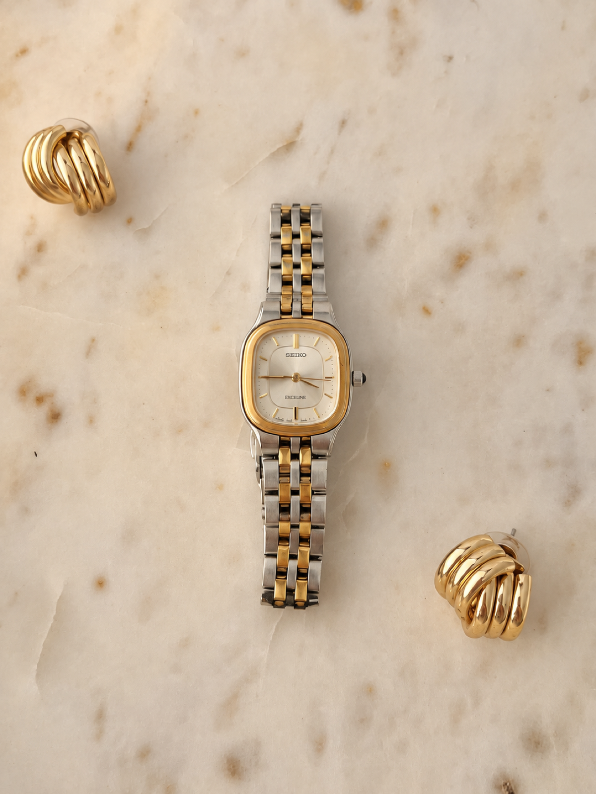 Seiko Exceline soft rectangular two tone watch with silver dial and gold bezel, straight on view with warm balanced lighting