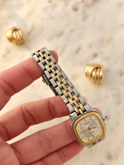 Handheld front detail of Seiko Exceline rectangular watch with two tone bracelet, gently warmed colour balance