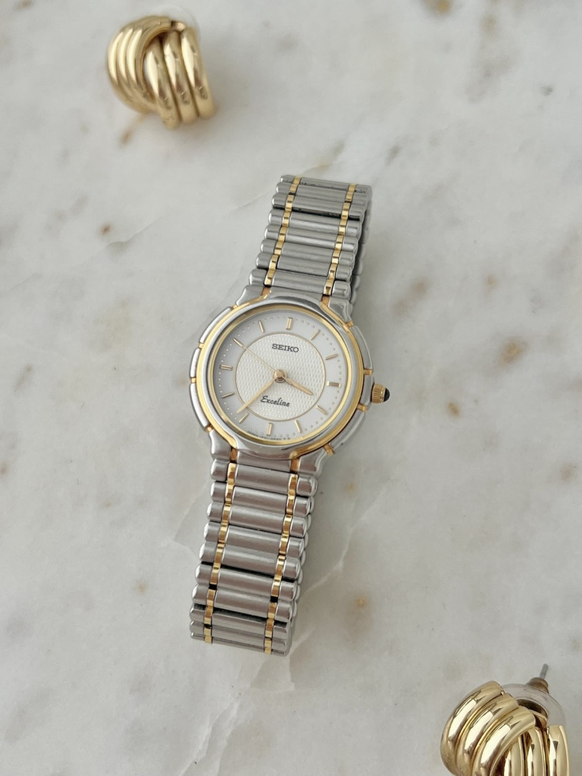 Angled front view of the Seiko Exceline two-tone bracelet watch with silver dial