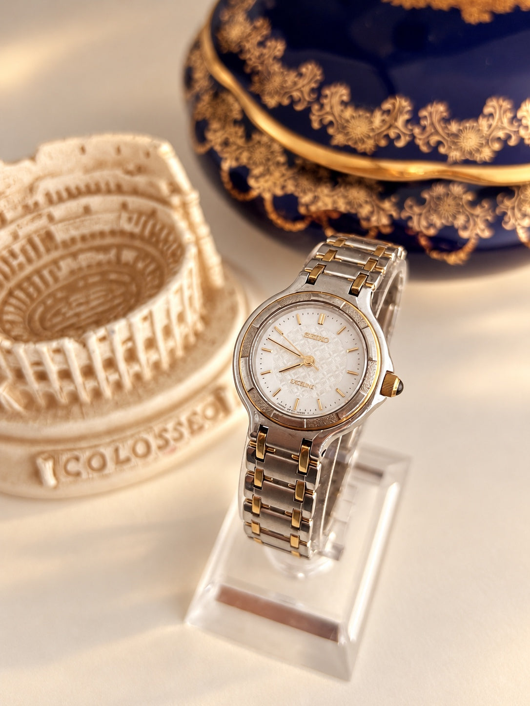 Seiko Exceline women’s watch with a white lattice dial, segmented bezel and two tone bracelet, shown at an angle.