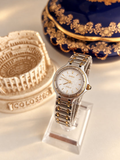 Seiko Exceline women’s watch with a white lattice dial, segmented bezel and two tone bracelet, shown at an angle.