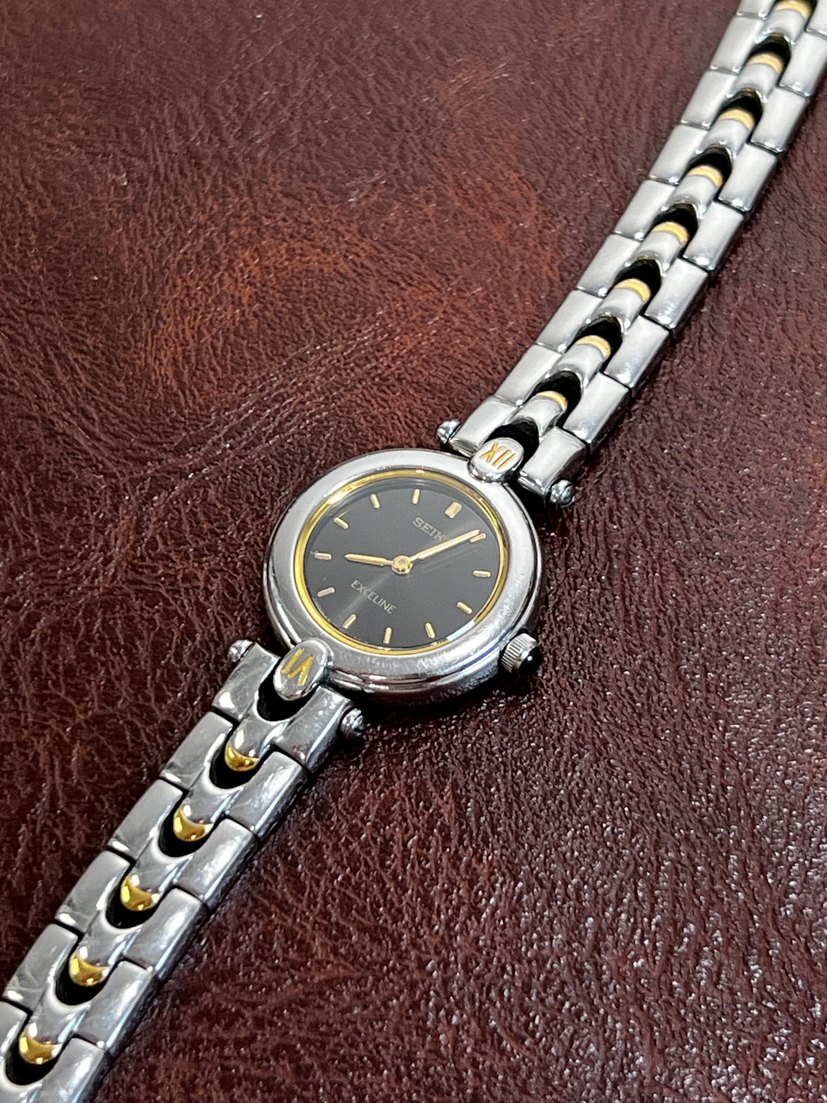 Seiko Exceline black dial watch with gold hands and a decorative two tone bracelet, product photograph 3.