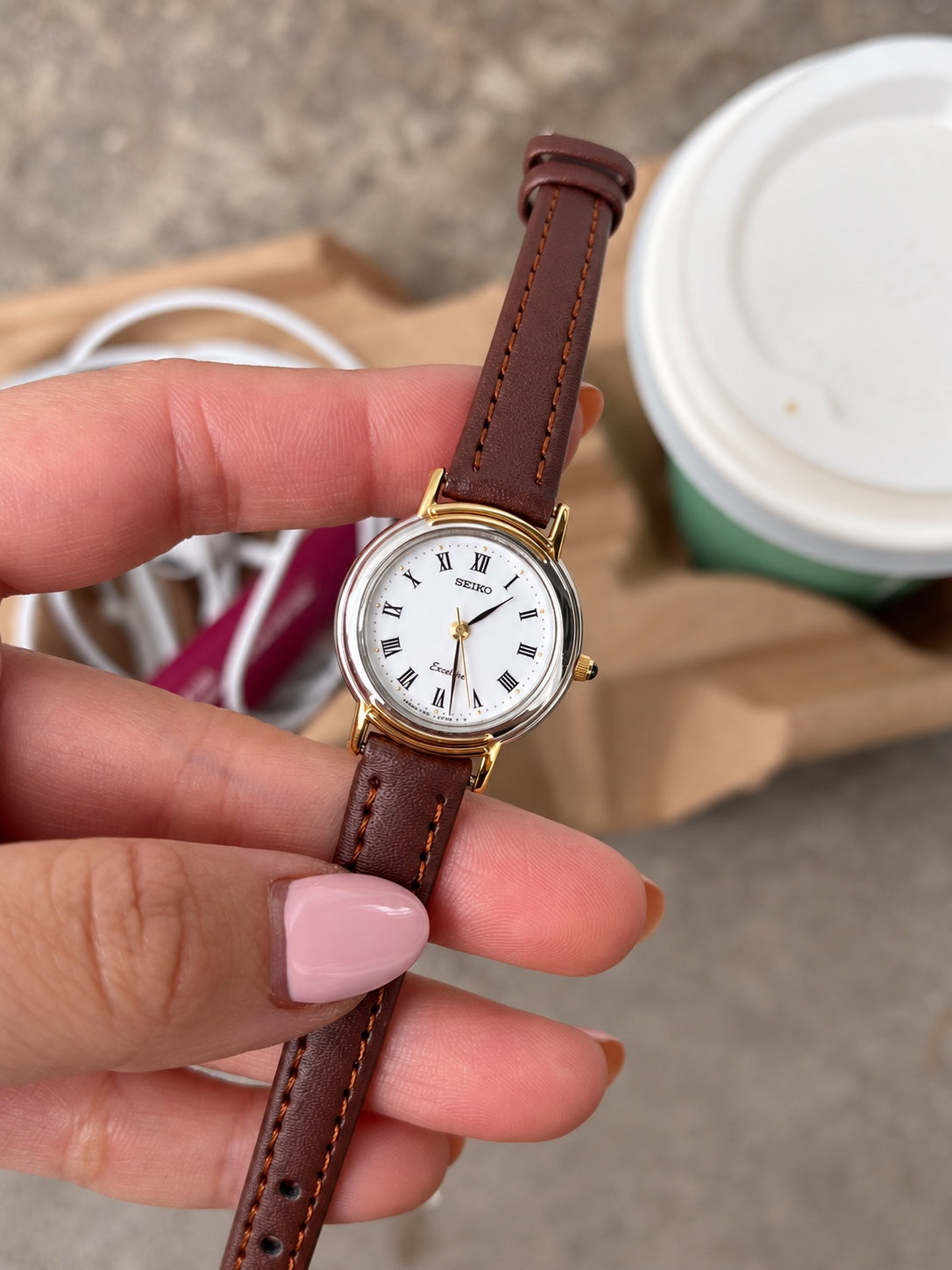 Seiko Exceline white Roman dial, two tone case and brown leather strap shown in hand.